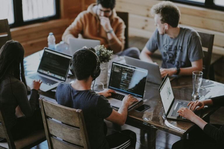 Marketing team planning a campaign around a table with laptops